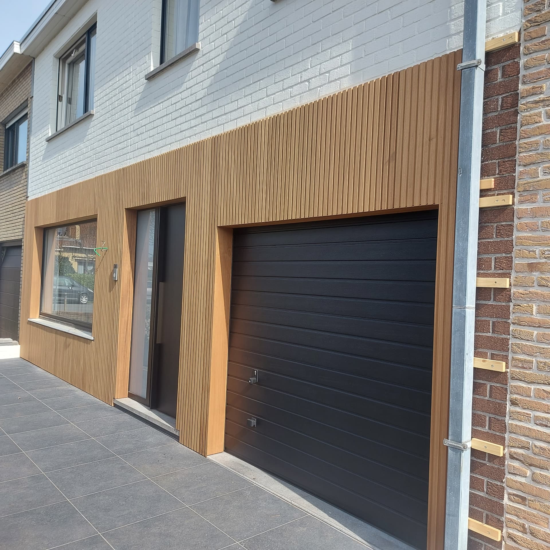 Houten gevelbekleding met zwarte garagepoort