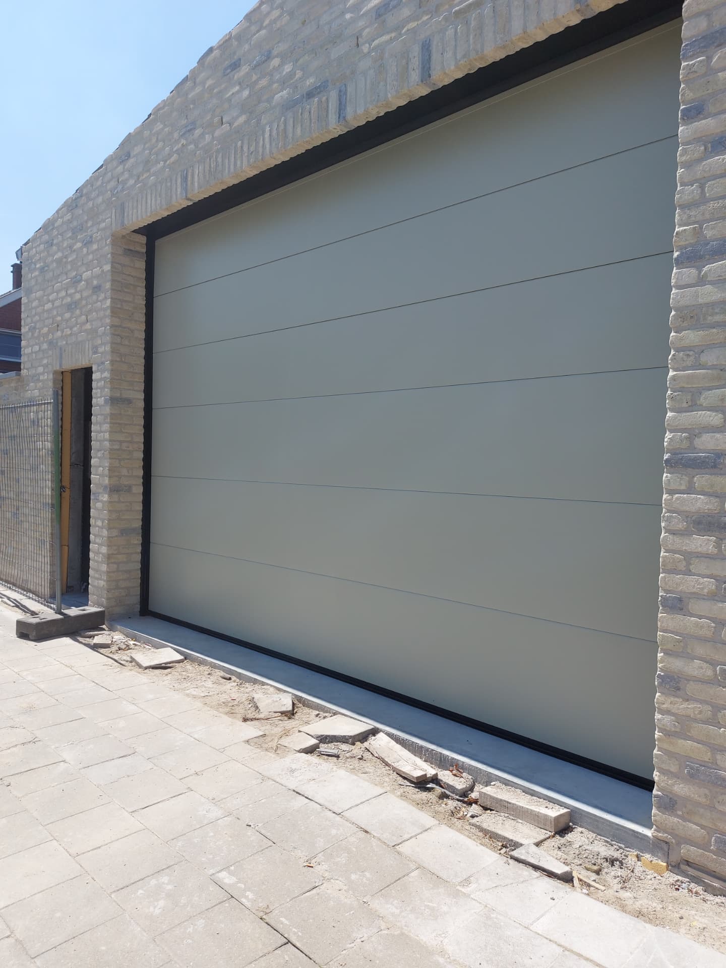 Grijze sectionale garagepoort in moderne gevel